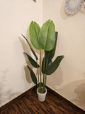 Home Sajawat artificial Bird of Paradise plant with large green leaves in a textured white pot for indoor decor.