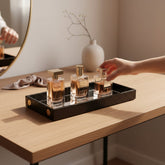 Home Sajawat black crocodile-textured faux-leather rectangular serving tray with a mirrored base holding perfume bottles