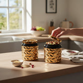 Home Sajawat set of two black and gold textured ceramic storage jars with soda-can style lids on a kitchen counter.