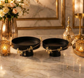 Home Sajawat matte black pedestal serving bowls with delicate gold floral rim accents on a marble table