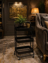 Home Sajawat matte black 3-tier rolling metal utility cart with mesh shelves in a sophisticated living room setting.