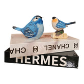 Home Sajawat decorative blue bird figurines with hand-painted details resting on stacked designer books.