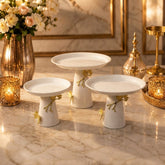 Home Sajawat set of three glossy white ceramic pedestal cake stands with gold butterfly and branch accents on marble