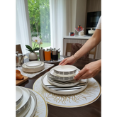 Home Sajawat white ceramic dinnerware set with black geometric pattern and gold rim. Includes plates and bowls.