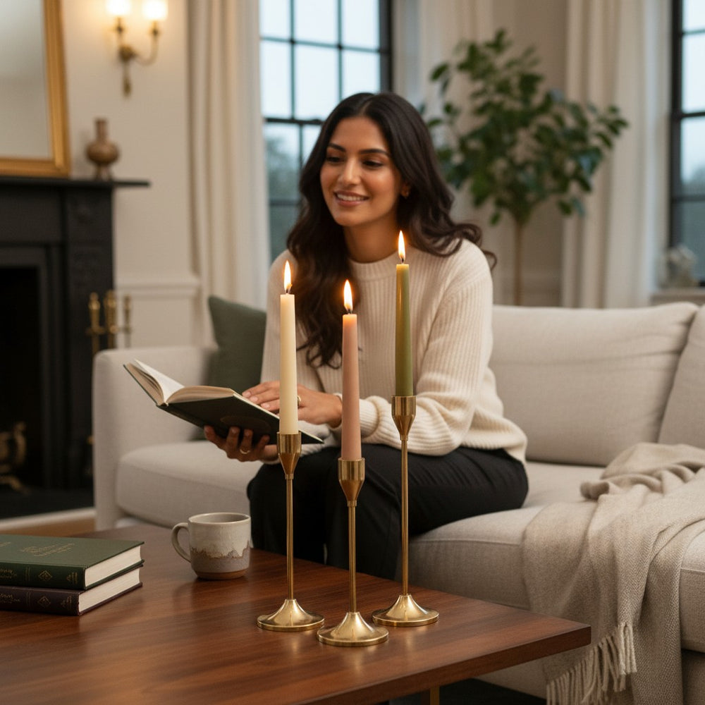 Home Sajawat set of three gold metal candlesticks with varying heights, holding cream, tan, and olive taper candles.