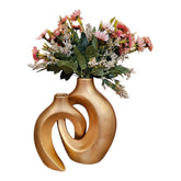Home Sajawat gold ceramic abstract hollow-center vase set with faux floral arrangement on a wooden table.