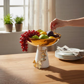Home Sajawat gold and cream pedestal serving bowl with butterfly accents holding fresh fruit on a wooden table
