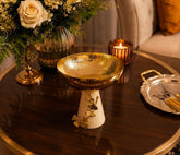 Home Sajawat decorative pedestal bowl with a hammered gold-tone finish and a cream ceramic base with ginkgo accents.