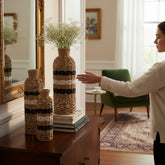 Home Sajawat set of three handwoven natural fiber floor vases with black and white striped accents on a wooden console