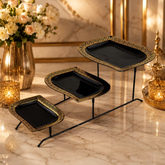 Home Sajawat three-tier serving stand with black ceramic plates, gold Greek key trim, and a minimalist black metal frame.