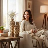 Home Sajawat set of three woven floor vases in tan and off-white, displayed in a cozy living room with a woman.