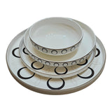 Home Sajawat white ceramic dinnerware set with black geometric circles and gold rim. Includes plates and bowls.