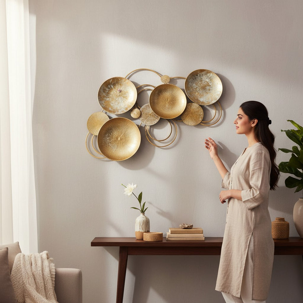 Home Sajawat abstract gold metal wall art sculpture with textured circular plates and rings. Modern metallic decor.