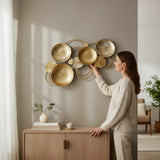 Home Sajawat abstract metal wall art sculpture with gold circular discs and silver accents. Textured surfaces and loops create movement.