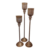 Home Sajawat set of three tall antique gold floor candle holders with white ornate detailing and flared bases.