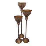 Home Sajawat set of three antique gold floor candle holders with white detailing and ornate cups and bases.