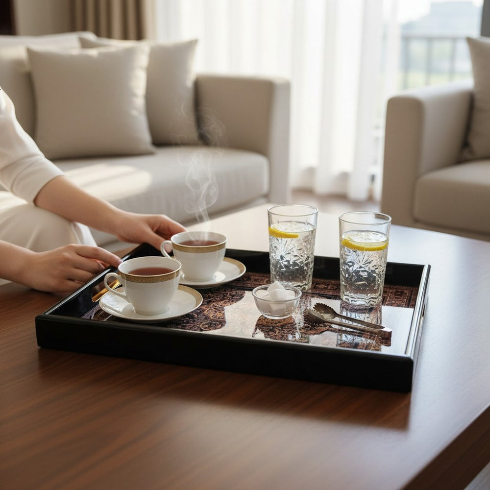 Home Sajawat decorative black serving tray with intricate patterns, holding tea cups and glasses on a wooden table.