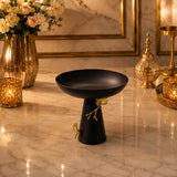 Home Sajawat matte black pedestal serving bowl with gold ginkgo leaf accents on a marble table