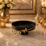 Home Sajawat matte black pedestal serving tray with elegant gold floral rim detailing on a marble table.