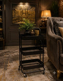 Home Sajawat matte black 3-tier rolling metal utility cart with mesh shelves in a sophisticated living room setting.