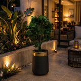 Home Sajawat decorative floor planter with a matte black woven texture and a polished gold-tone rim on a patio.