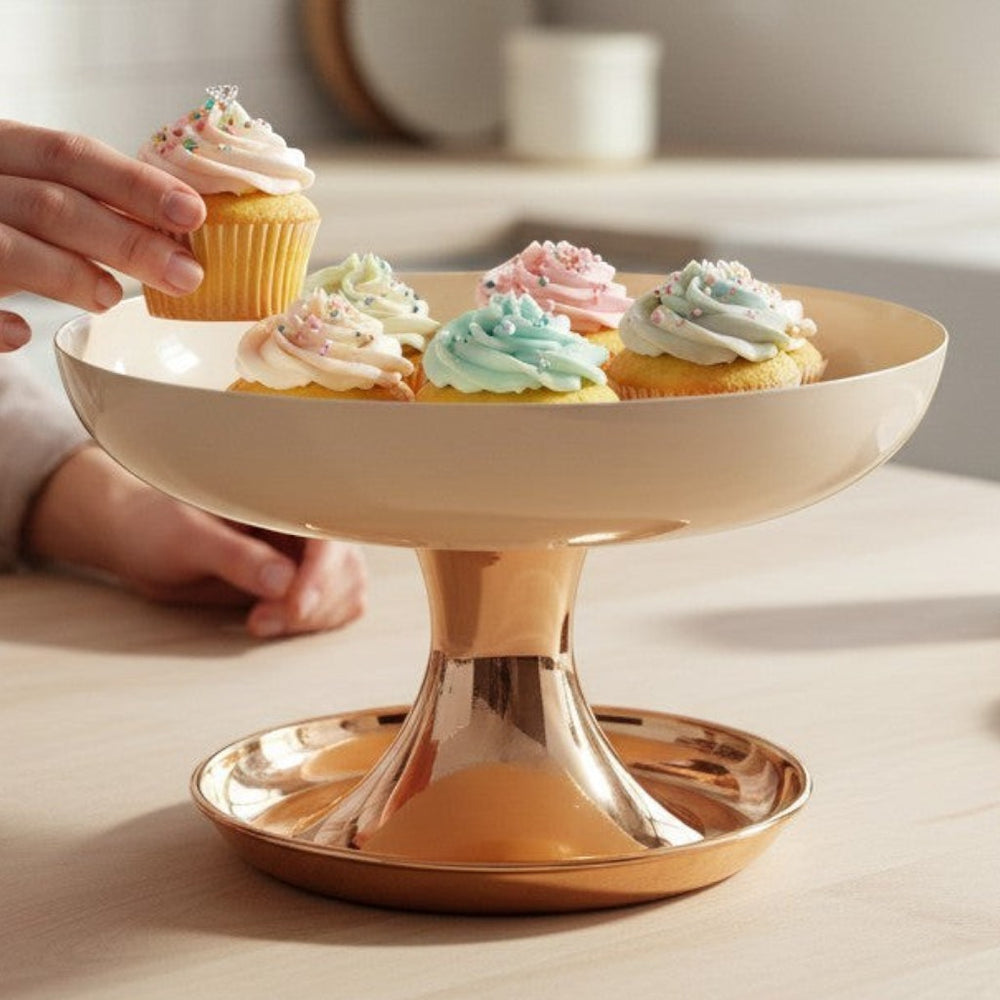 Home Sajawat cream pedestal bowl with gold base holding cupcakes on a wooden kitchen table