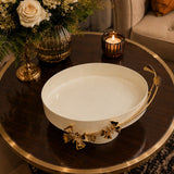 Home Sajawat cream metal serving tray with gold floral butterfly accents on a dark wooden table with flowers and candle