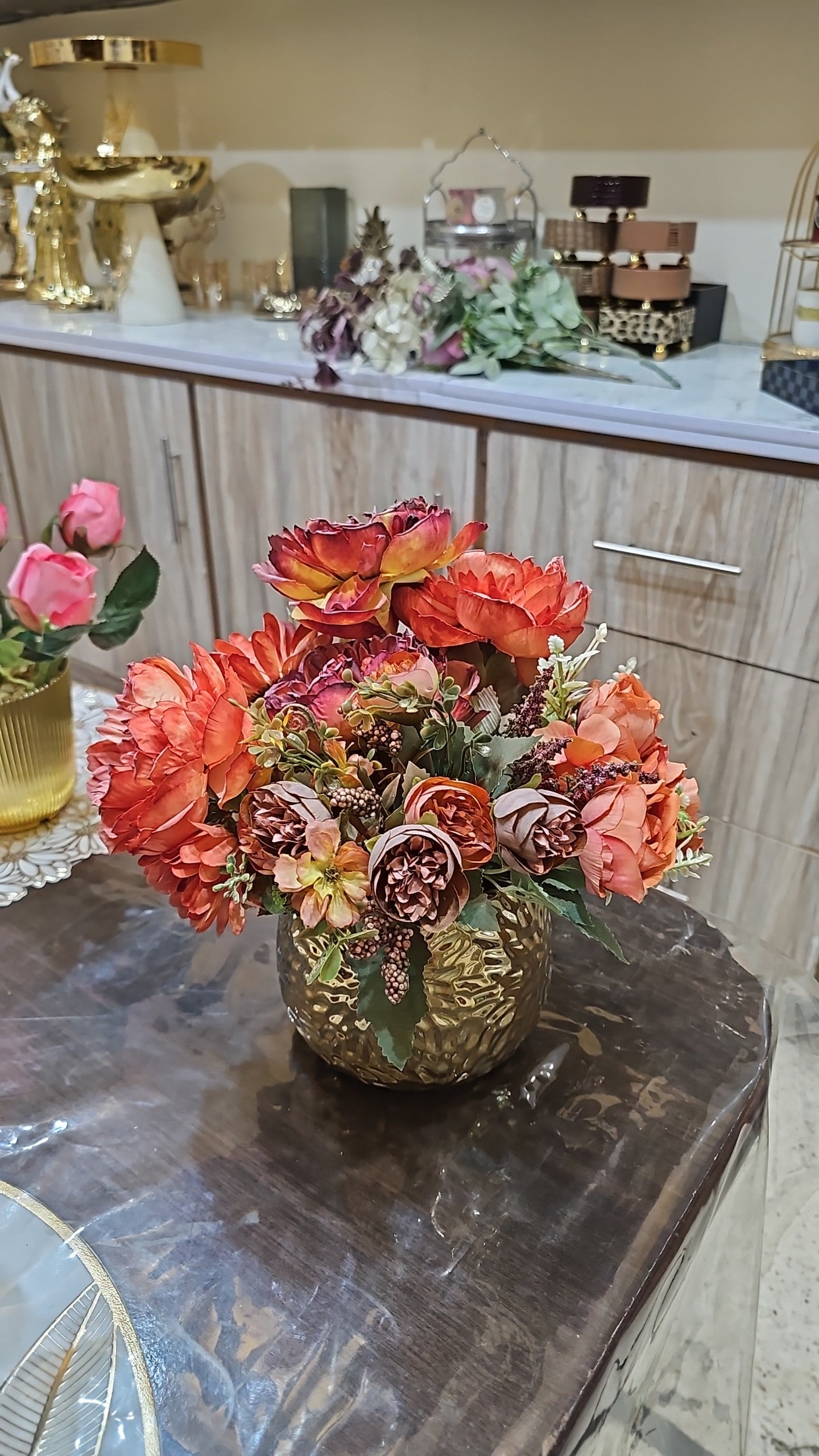 Home Sajawat artificial floral arrangement with orange and crimson roses in a textured gold metallic vase.