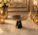 Home Sajawat decorative cake stand with a textured gold plate, matte black base, and elegant ginkgo leaf detailing.