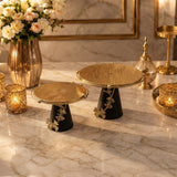 Home Sajawat decorative gold and black cake stands with ginkgo leaf accents on a marble table with floral decor.