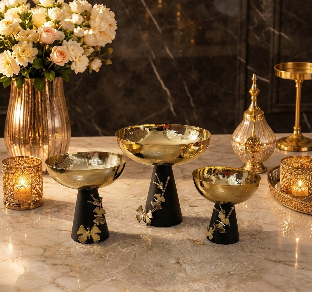 Home Sajawat set of three decorative pedestal bowls with hammered gold-tone basins and matte black floral bases.
