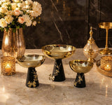 Home Sajawat set of three decorative pedestal bowls with hammered gold-tone basins and matte black floral bases.