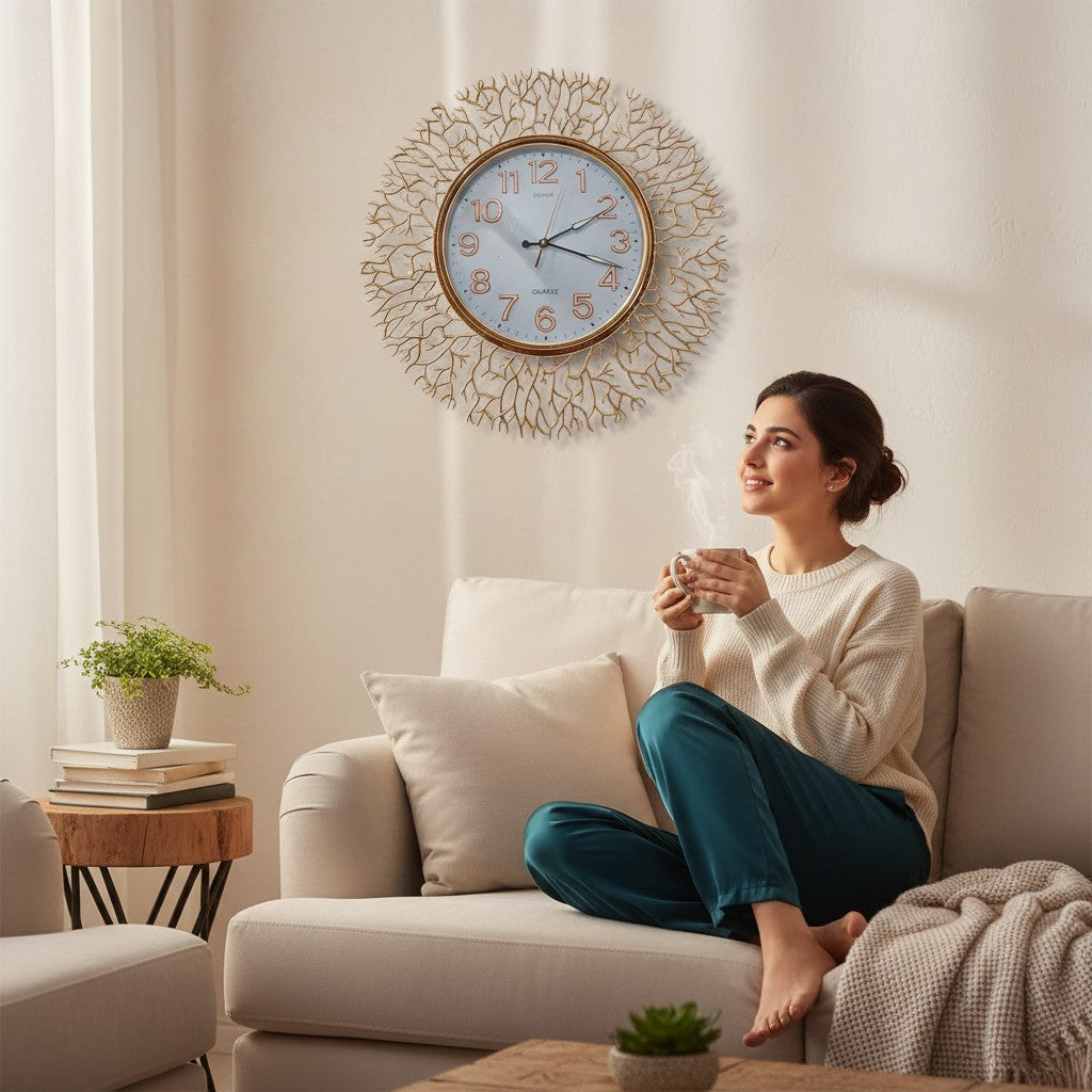Home Sajawat gold metal wall clock with intricate branch design and white face with Arabic numerals.