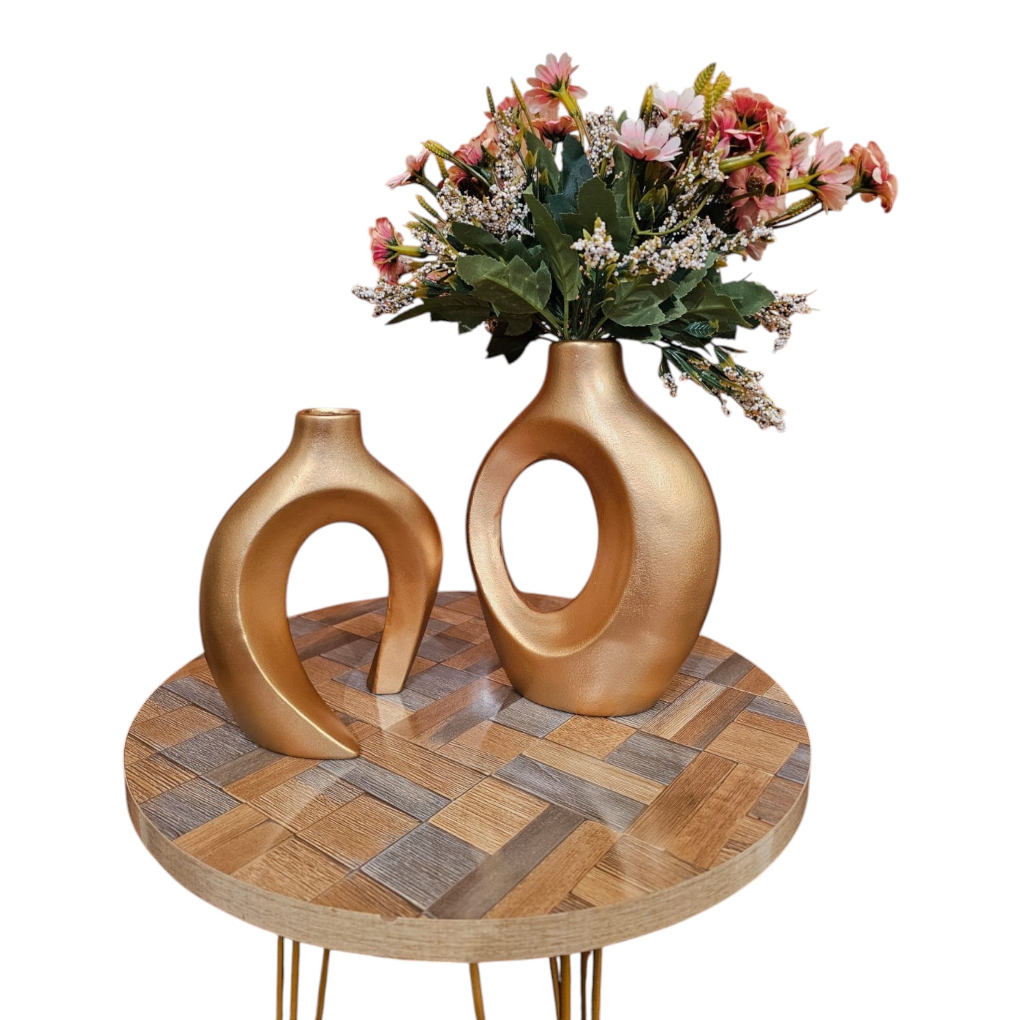 Home Sajawat set of two gold ceramic abstract hollow-center vases with faux floral arrangement on a wooden table.
