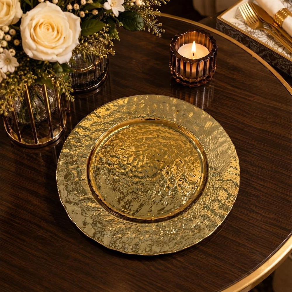 Home Sajawat gold hammered charger plate on a dark wooden table with a floral centerpiece and lit candle
