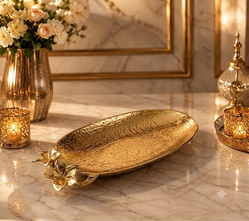 Home Sajawat gold hammered metal serving tray with floral accents on a marble table with candles and flowers