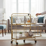 Home Sajawat gold metal two-tier bar cart with clear acrylic shelves and ribbed panels, on wheels.