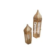 Home Sajawat set of two gold metal Moroccan-inspired lanterns with intricate cut-out designs and clear glass panels.