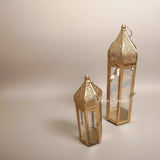 Home Sajawat set of two gold metal Moroccan-inspired lanterns with intricate cut-out designs and clear glass panels.