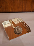 Home Sajawat gold metal napkin holder with laser-cut floral edges and a sparkling jewel-encrusted floral weight.