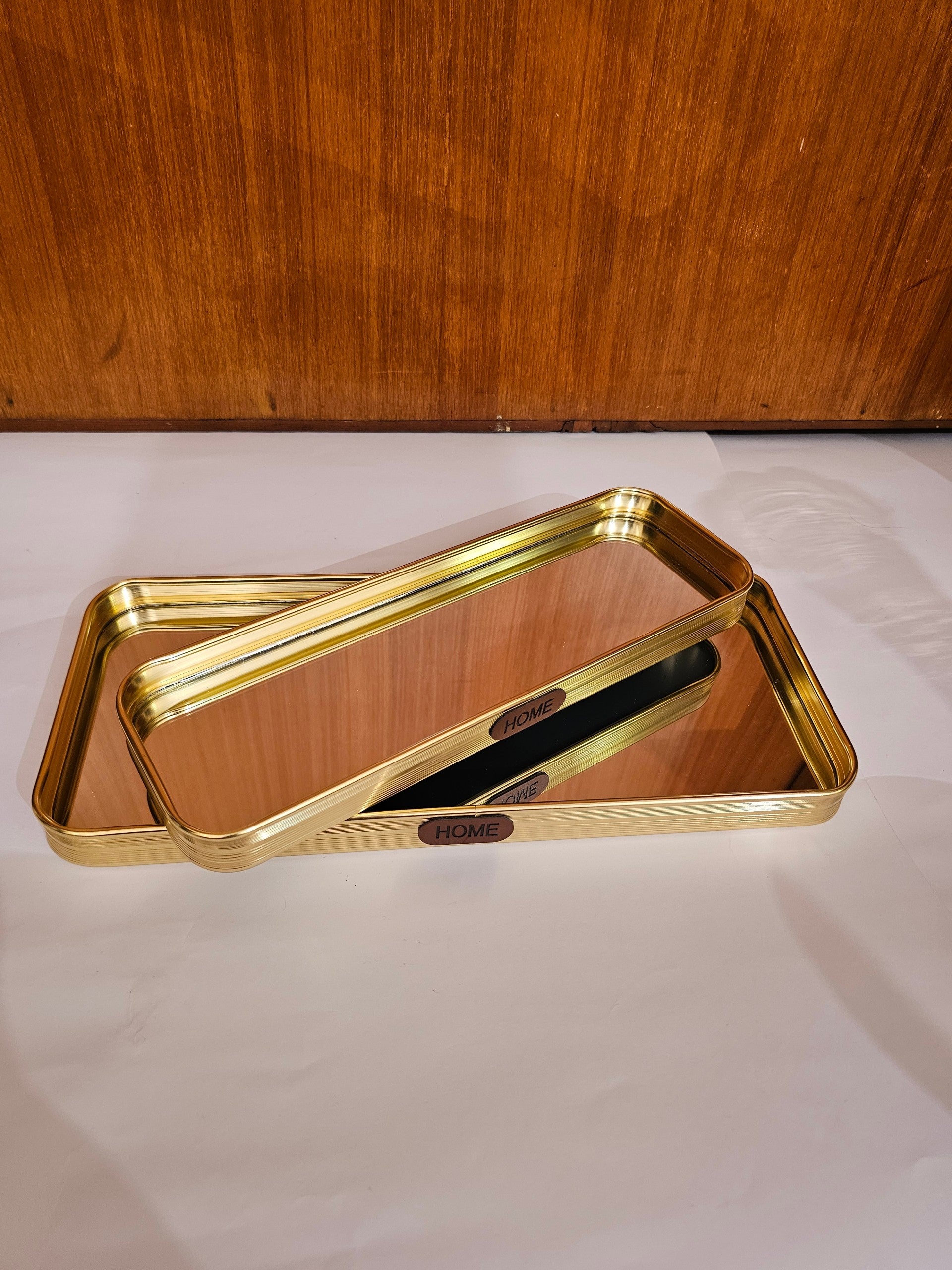 Home Sajawat rectangular gold metal serving tray with a mirrored base and HOME label for vanity or home decor.