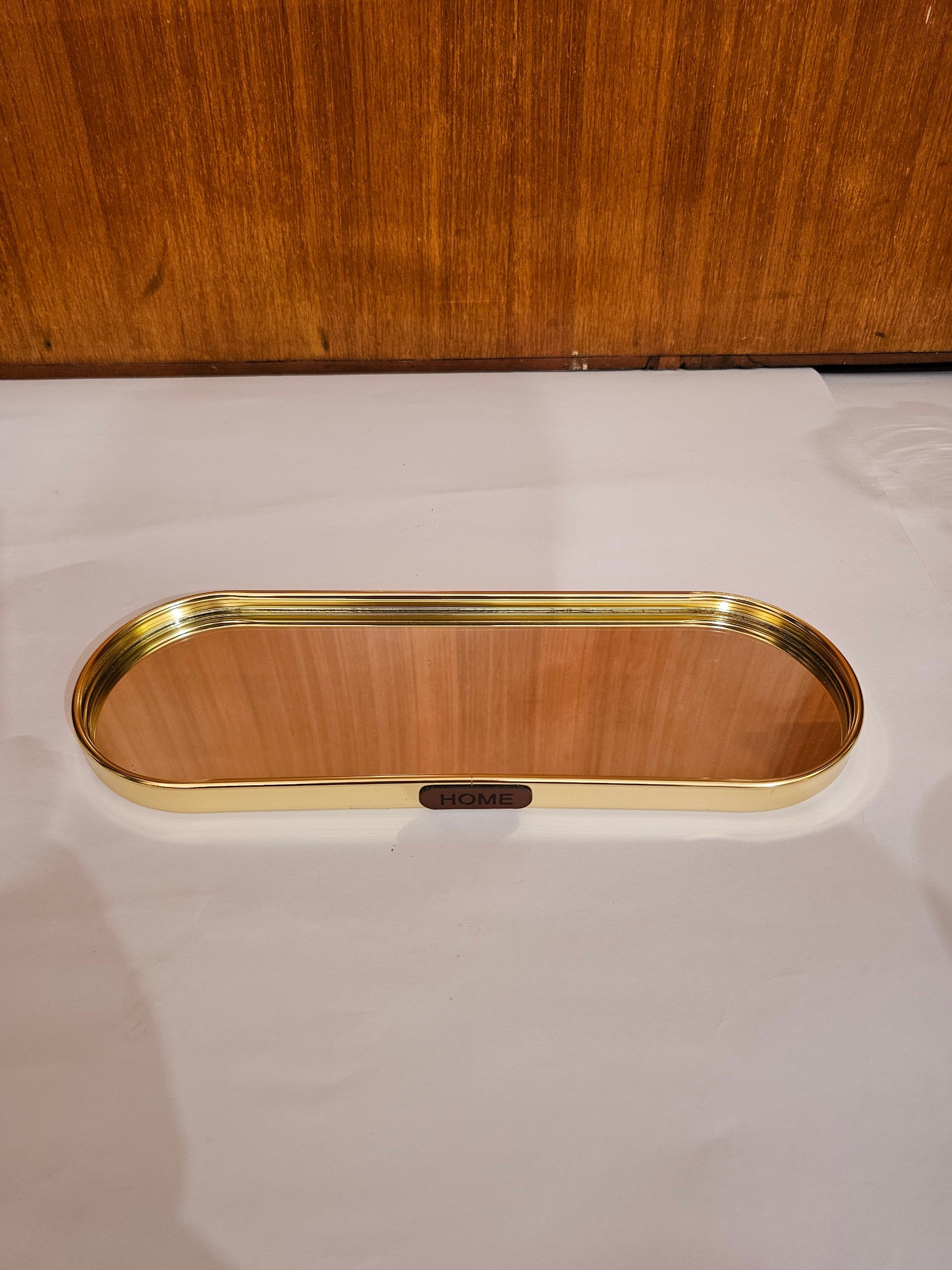 Home Sajawat oval mirrored vanity tray with a polished gold-tone metal frame and HOME label detail.