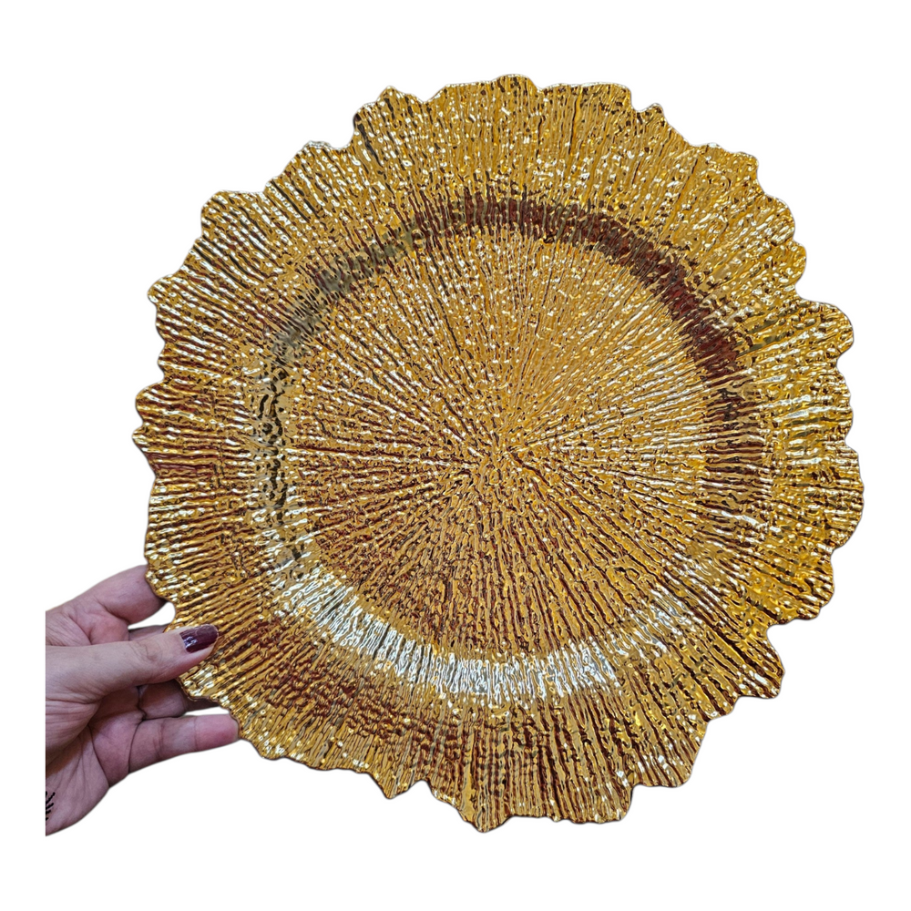 Home Sajawat gold charger plate with a textured, sunburst-inspired rim held by a hand for a formal table setting.