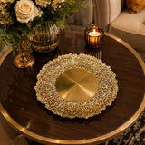 Home Sajawat decorative gold charger plate with a textured, organic leaf-inspired rim on a dark wood table.