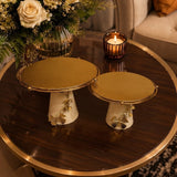 Home Sajawat set of two gold and white ceramic cake stands with butterfly accents on a dark wood coffee table