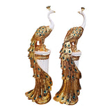 Home Sajawat set of two gold and white peacock statues on fluted pedestals with teal gemstone feather accents.