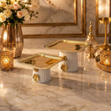 Home Sajawat decorative square pedestal serving trays with white fluted ceramic bases and polished gold-tone metal tops.