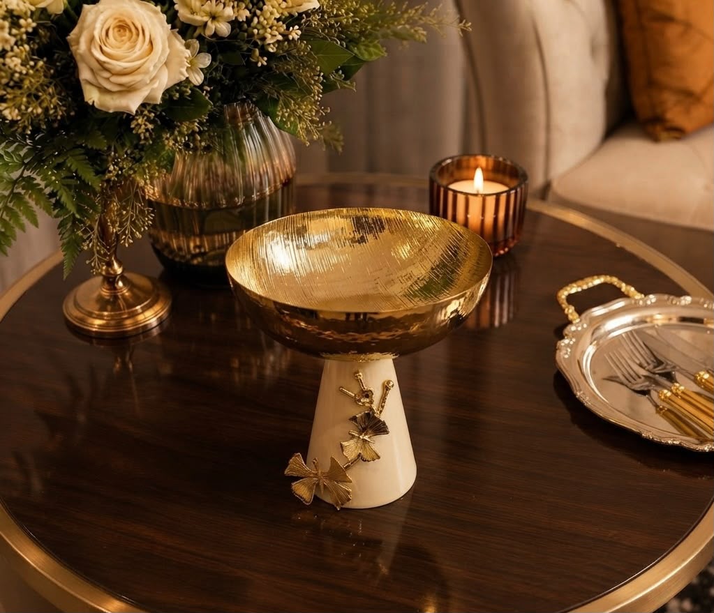 Home Sajawat decorative pedestal bowl with a hammered gold-tone finish and a cream ceramic base with ginkgo accents.