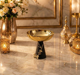 Home Sajawat decorative pedestal bowl with a hammered gold-tone finish and a matte black base featuring floral motifs.