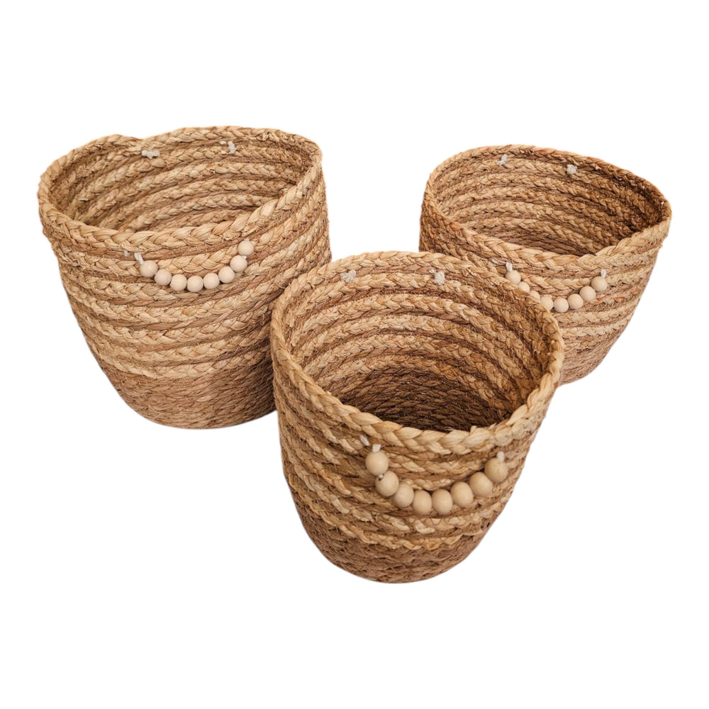 Home Sajawat set of three handwoven seagrass storage baskets with natural wooden bead accents and coiled texture.